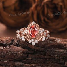 a ring with an orange stone surrounded by white and pink diamonds on top of a piece of wood