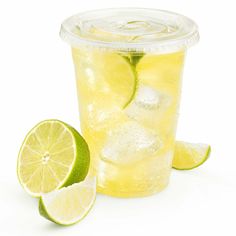 a glass with lemonade and limes next to it