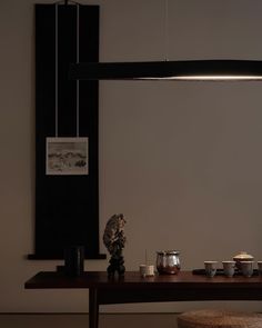 a wooden table topped with cups and saucers next to a wall mounted light fixture