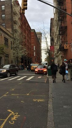 people are walking down the street in front of cars