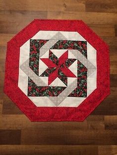 a red and white quilted table topper on a wooden floor with wood floors