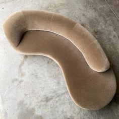 a curved couch sitting on top of a cement floor