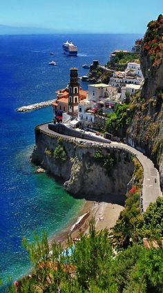 a scenic view of the ocean with boats in the water and buildings on the cliff