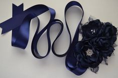 "Five handmade fabric flower arrange into a perfect arrangement of flowers to be worn at the waist. Three open blooms are finished with pearl and rhinestone centers. Lace and navy tulle finish some of the flowers. Two closed blooms add to the arrangement. Lace and tulle \"leaves\" finish the piece. On a coordinating, double faced satin ribbon. Flower cluster measures approximately 4x6 inches. Ribbon is 1.5 inches wide. Standard length is 3 yards long and will fit most. Please let me know if you Elegant Blue Party Sashes, Elegant Sashes With Handmade Flowers For Party, Elegant Handmade Flower Sashes For Party, Satin Ribbon Flower, Blue Sash, Arrangement Of Flowers, Bridesmaid Sash, Navy Flowers, Flower Cluster