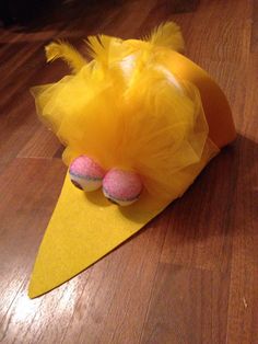 a yellow cone with some pink donuts in it sitting on the floor next to a pair of scissors