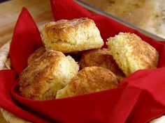 a red basket filled with biscuits on top of a wooden table