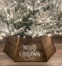 a merry christmas sign on the side of a wooden box in front of a tree