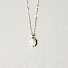 This necklace features the sweetest little crescent moon charm on dainty but sturdy sterling silver cable chain. The charm is about 13mm long (including the loop) and about 7mm wide. A perfect everyday necklace! It is fastened with a sterling spring ring clasp and you can choose your desired length from the drop-down menu above. You can find more celestial jewelry here: www.etsy.com/ca/shop/juliegarland/search?search_query=celestial+jewelry Dainty Silver Moon Charm Necklaces, Dainty Silver Moon Charm Necklace, Silver Crescent Sterling Silver Charm Necklace, Dainty Half Moon Charm Necklace, Silver Half Moon Charm Necklaces, Silver Dainty Moon Charm Necklace, Silver Half Moon Charm Necklace, Sterling Silver Moon Charm Necklace For Gift, Dainty Silver Necklace With Moon Charm