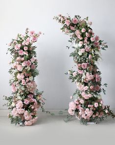 two floral archways with pink and white flowers on the top, one in the middle