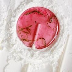 a pink object with writing on it sitting in the middle of white powdered paper