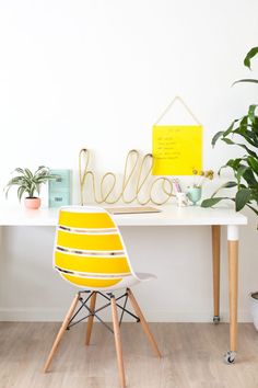 a yellow chair sits in front of a white desk with a hello sign on it