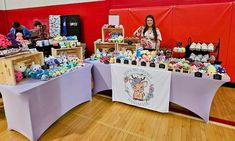 a woman standing in front of a table with stuffed animals on it and other items for sale