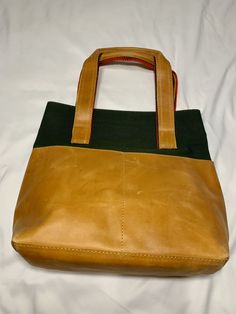 Genuine Leather Tote along Bag. A mixed media bag big enough for all the essentials. With an interior zip pocket for added storage and three exterior pockets for easy access. Material- Genuine Leather and Canvas On-the-go Bag With Zipper Pocket And Pouch Shape, Practical Tote Travel Bag With Removable Pouch, Green Tote Bag With Zipper Pocket, Green Tote Bags With Zipper Pocket, Green Everyday Satchel With Zipper Pocket, Everyday Green Satchel With Zipper Pocket, On-the-go Pouch Travel Bag With Zipper Pocket, Green Canvas Bags With Zipper Pocket, Modern Bags With Leather Handles And Recycled Leather