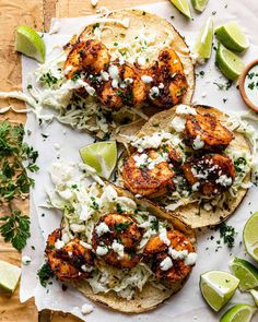 grilled shrimp tacos with lime wedges and cilantro sauce on top