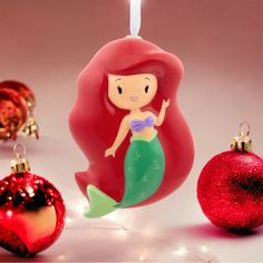 an ornament shaped like a mermaid next to christmas ornaments