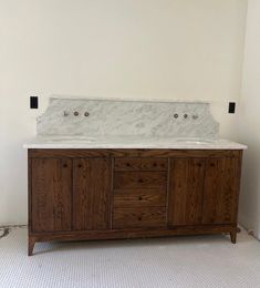 a bathroom vanity with marble top and two sinks in the middle, against a white wall