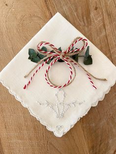 a white napkin with red and green twine tied to it on top of a wooden table