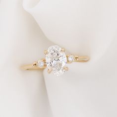 an oval diamond engagement ring on top of a white cloth