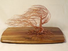 a wooden cutting board with a wire tree on it's top and roots in the middle