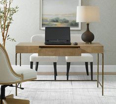 a laptop computer sitting on top of a wooden desk next to a lamp and chair