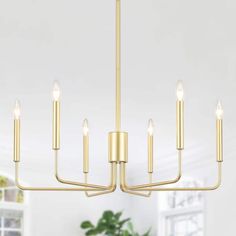 a gold chandelier with five candles hanging from the ceiling in a living room