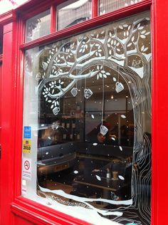 a red store front with the reflection of a tree in it's glass window