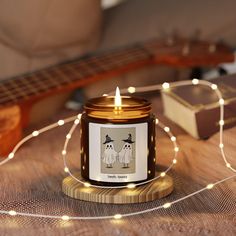 a candle that is sitting on top of a table next to some string lights and a guitar