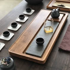 a wooden table topped with two cups and trays filled with tea on top of it