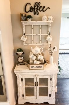 a white cabinet sitting next to a wall with coffee mugs on it