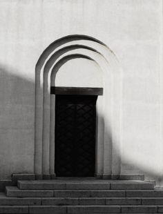 a black and white photo of an arch on the side of a building with steps leading up to it