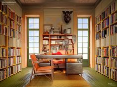 a room with many bookshelves full of books and a desk in the middle