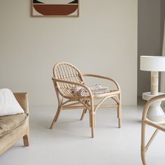 two wicker chairs and a lamp in a room with white flooring on the walls