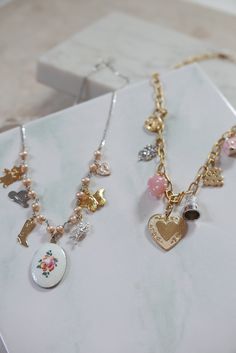 This charm necklace is so sweet and perfect, we can't even handle it. Features mostly vintage mixed-metal charms, hanging on pearls and sterling silver curb chain - to give it just a touch of edginess. 7 charms hang from a strand of sterling freshwater pearls, with a pinkish hue: gold plated vintage teddy bear stainless vintage western hat gold plated cowgirl boot enameled, hand-painted rose charm from the 1960s in center silver plated vintage angel charm gold plated vintage butterfly charm enam Whimsical Pendant Necklace With Vintage Charm, Whimsical Vintage Charm Pendant Necklace, Whimsical Metal Jewelry With Vintage Charm, Whimsical Vintage Charm Jewelry, Whimsical Vintage Charm Pendant Jewelry, Vintage Style Metal Necklaces With Charms, Vintage Metal Charm Necklace, Dainty Metal Necklaces With Vintage Charm, Vintage Charm Necklace With Dangling Pendants