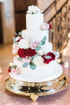 a three tiered wedding cake with red and white flowers