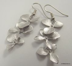 These silver orchid earrings are so sophisticated, delicate and simply stunning. They are perfect for any occasion and they make a wonderful bridal gift - for the bride or the bridesmaids! These earrings feature three lightweight, cascading matte silver plated orchids. They are finished off with stainless steel ear wires, for those with sensitive ears. The ear wires can be switched out to silver plated clip-ons, for those with non-pierced lobes. Simply select that option before adding to your ca Hypoallergenic Sterling Silver Flower Earrings For Wedding, Dainty Silver Bridal Earrings For Bridesmaid Gift, Silver Dainty Bridal Earrings For Bridesmaid Gift, Delicate Silver Earrings For Bridesmaid Gift, Elegant Orchid Flower Earrings, Silver Flower Drop Earrings For Bridesmaid Gift, Delicate Silver Flower Earrings For Wedding, Dainty Silver Flower Earrings For Wedding, Elegant Nickel-free Flower Earrings For Wedding