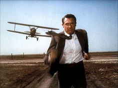 a man in a suit and tie is walking with an airplane on the ground behind him