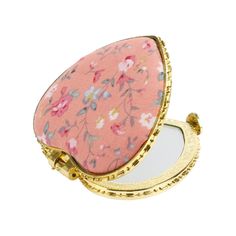 a compact mirror sitting on top of a white surface next to a gold ring holder