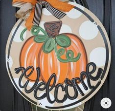 a welcome sign is hanging on the front door with polka dot ribbon and pumpkins