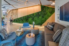 a living room filled with lots of furniture and walls covered in green plants on the wall