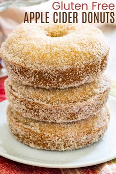 three donuts stacked on top of each other on a white plate with sugar sprinkles