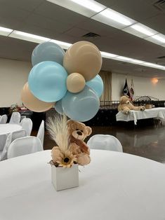 a bunch of balloons that are on top of a table in a room with white tables and chairs