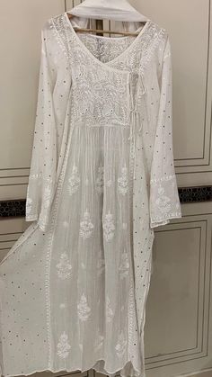 Discover the epitome of timeless elegance with our Pure Cotton Silk Angarkha Set, adorned with vintage Chikankari Ek Taar embroidery. This exquisite piece is further embellished with intricate Mukaish and Pitta work, creating a luxurious blend of tradition and modernity. The kurta comes with a matching dupatta and lining, and you have the option to choose between churidhaar or pants for the bottoms, allowing you to tailor the set to your personal style. Each set is customizable to any size, ensuring a perfect fit for everyone. Please send your size specifications before placing your order. Embrace the allure of heritage craftsmanship with this stunning ensemble, perfect for any special occasion. Silk Sherwani With Chikankari Embroidery For Navratri, Traditional Cotton Silk Kaftan For Festivals, Bohemian Anarkali Set With Zari Work For Transitional Season, Cotton Silk Traditional Wear With Dabka Work For Reception, Transitional Bohemian Anarkali Set With Zari Work, Traditional Chanderi Kurta For Reception, Elegant Cotton Silk Kurta With Cutdana, Designer Anarkali White Kaftan, Designer Wear Kaftan With Intricate Embroidery For Navratri