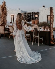 the back of a woman's wedding dress as she stands in front of a table