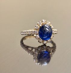 "DeKara Designs Collection Art Deco Inspired Extremely Elegant Halo Opal Diamond Engagement Ring. Metal- 90% Platinum, 10% Iridium. Stones- 1 Natural Oval Cabochon Ceylon Blue Sapphire 2.85 Carats, 26 Round Diamonds F-G Color VS1 Clarity 0.65 Carats. Size- 4-12 An Amazing Art Deco Inspired Ceylon Blue Sapphire Halo Diamond Engagement Ring Made in 18K Yellow Gold. The ring features a beautiful a beautiful Ceylon Blue Sapphire that is Oval in shape and cabochon cut. The sapphire is gracefully set Classic Sapphire Cabochon Rings, Luxury Yellow Gold Gemstone Cabochon, Luxury Diamond Cabochons For Wedding, Exquisite Formal Gemstone Cabochons, Elegant White Gold Cabochons For Formal Occasions, Formal Hallmarked Diamond Cabochons, Luxury White Gold Diamond Cabochons, Timeless Diamond Rings With Cabochon, Formal Fine Jewelry Gemstone Cabochons