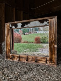 a mirror sitting on top of hay in front of a barn door with a cow