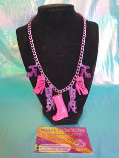 a necklace with pink boots and purple chains on top of a black mannequin