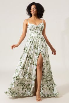 a woman in a white and green floral print dress is posing for the camera with her legs spread out