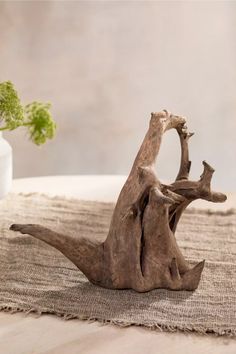 a small wooden animal sitting on top of a table next to a potted plant