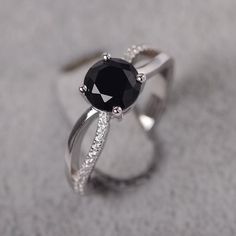 a black and white diamond ring sitting on top of a gray surface with diamonds around it