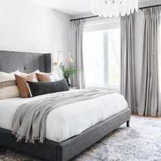 a bedroom with a large bed and a chandelier hanging from the ceiling